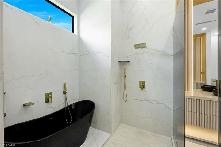 Full bathroom with a soaking tub, a marble finish shower, and vanity