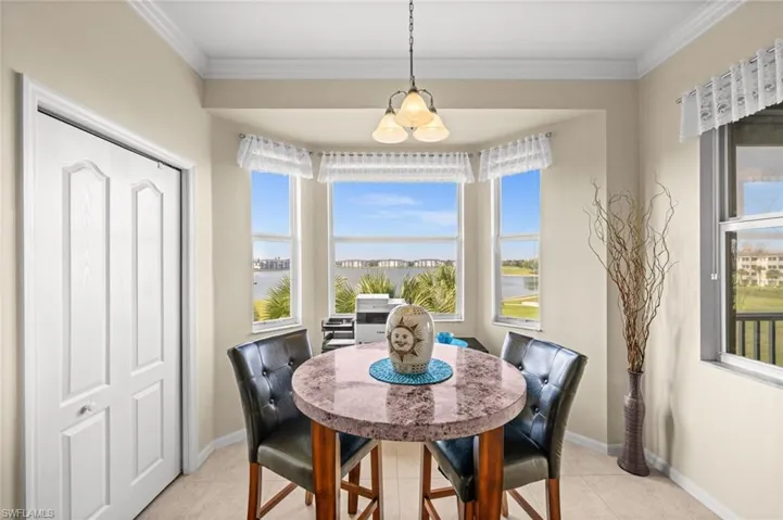 Dining space with a water view, crown molding, and light tile patterned floors