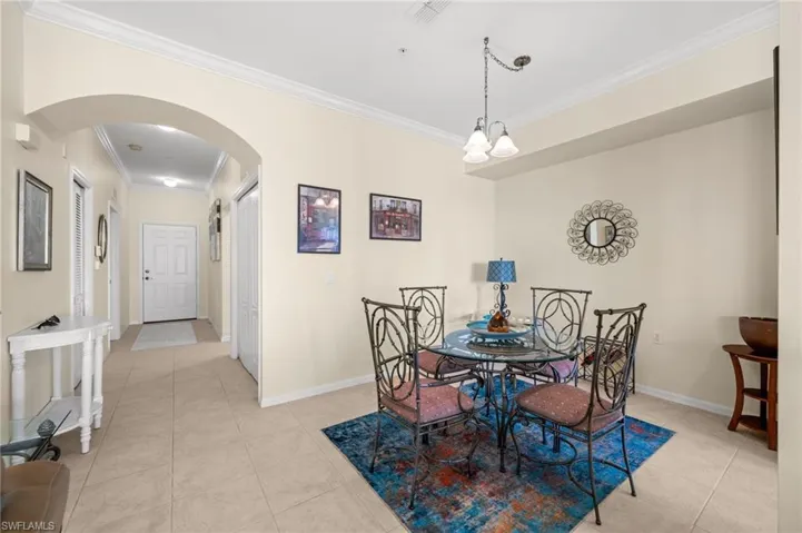 Dining area featuring arched walkways, crown molding, and light tile patterned floors