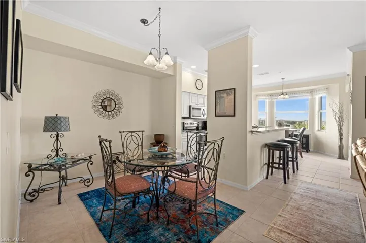 Dining area with a chandelier, ornamental molding, light tile patterned flooring, and recessed lighting