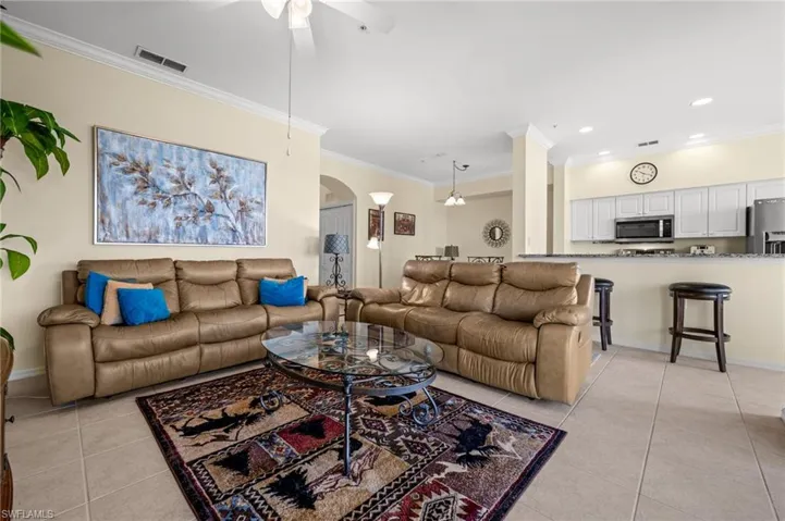 Living area featuring crown molding, arched walkways, light tile patterned floors, a ceiling fan, and recessed lighting