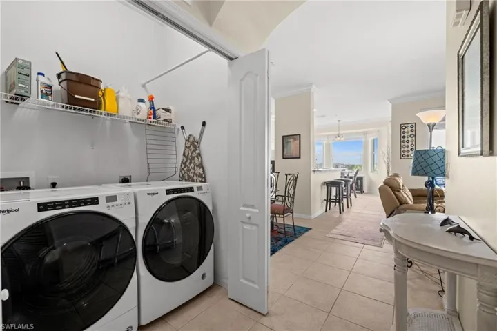 Washroom featuring light tile patterned floors, ornamental molding, and washer and dryer