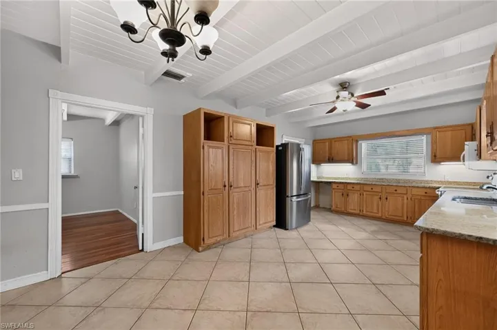 Spacious kitchen featuring wood-finish cabinetry, stainless steel refrigerator, tile flooring, and ample counter workspace