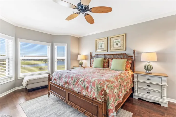 Primary Bedroom with beautiful view out the bay windows  with impact glass, hand scraped wood floors, crown molding and recently painted.
