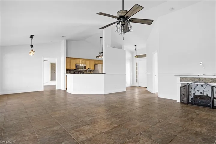 Unfurnished living room with a sink, baseboards, high vaulted ceiling, and ceiling fan