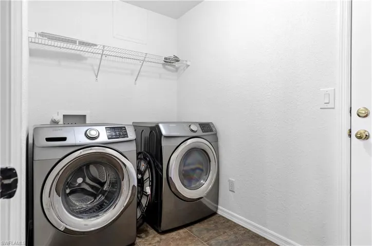 Washroom featuring washing machine and dryer, baseboards, and laundry area