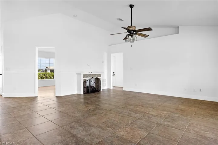 Unfurnished living room with a ceiling fan, baseboards, high vaulted ceiling, and a fireplace