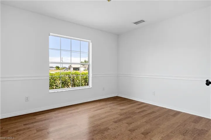 Spare room with baseboards, wood finished floors, and visible vents