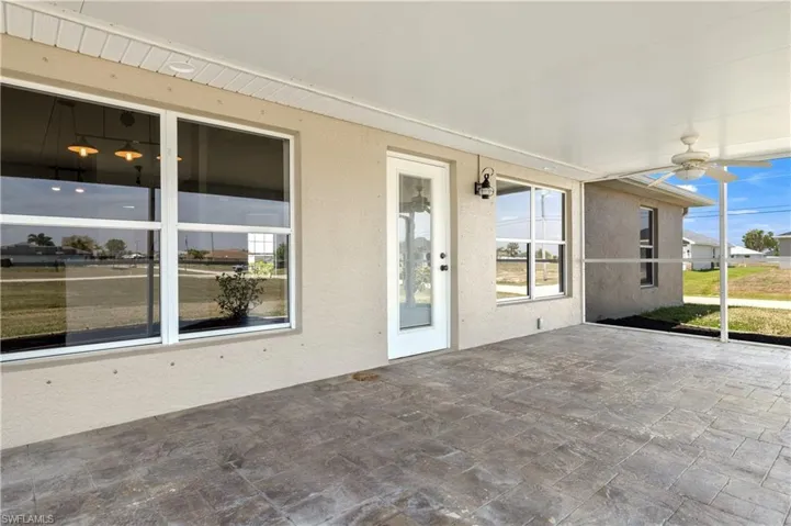 Unfurnished sunroom with a textured wall, a ceiling fan, stone tile flooring, and a healthy amount of sunlight
