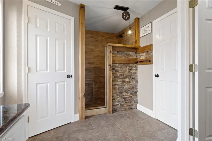 Bathroom featuring baseboards, a shower stall, and vanity