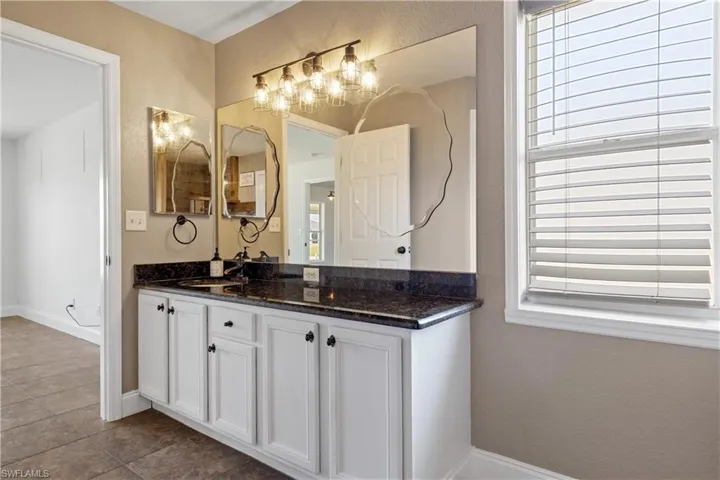 Bathroom with baseboards, a textured wall, vanity, and tile patterned floors