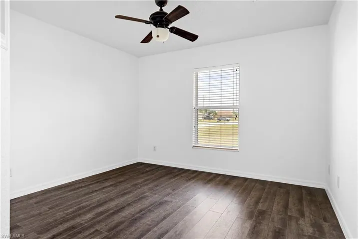 Unfurnished room with dark wood finished floors, baseboards, and ceiling fan