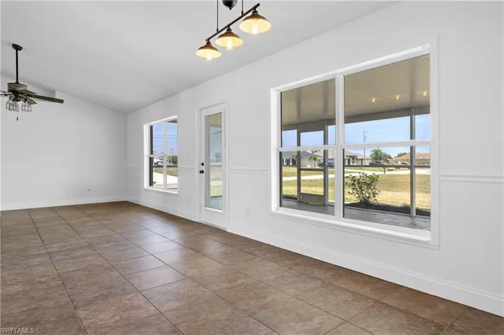 Unfurnished room featuring lofted ceiling, a ceiling fan, a wealth of natural light, and tile patterned flooring