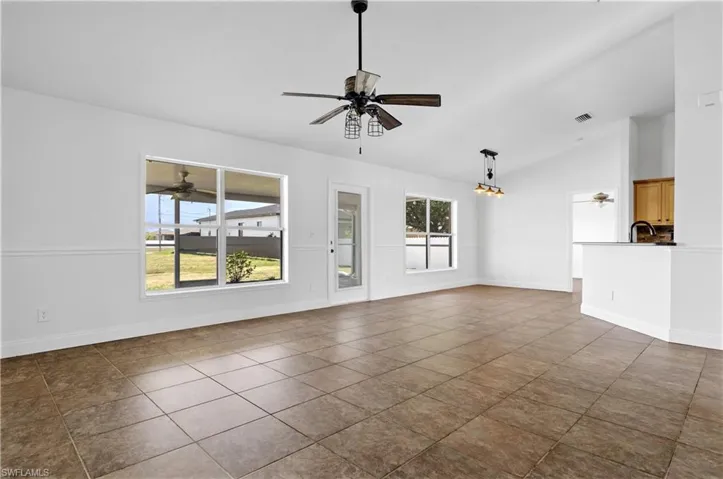 Unfurnished living room with lofted ceiling, baseboards, a ceiling fan, and visible vents