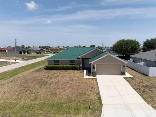 View of front facade with fence, a front lawn, a residential view, concrete driveway, and an attached garage