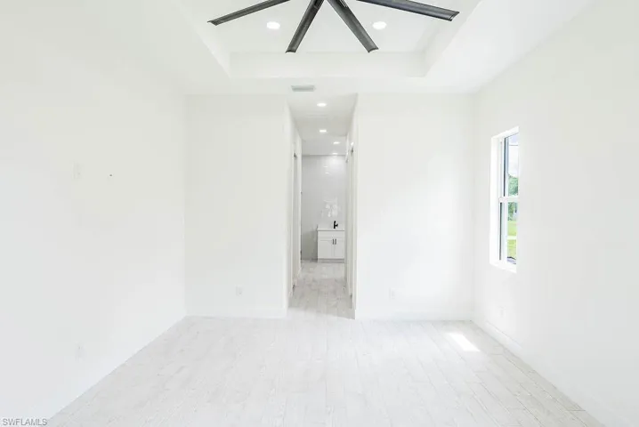 Unfurnished room featuring a raised ceiling, light hardwood / wood-style flooring, and ceiling fan