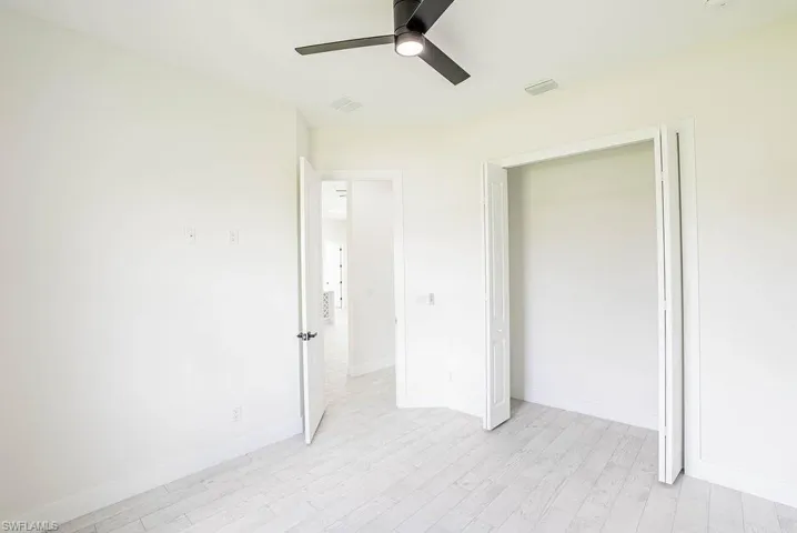 Kitchen with white cabinets, a center island with sink, sink, backsplash, and light hardwood / wood-style floors