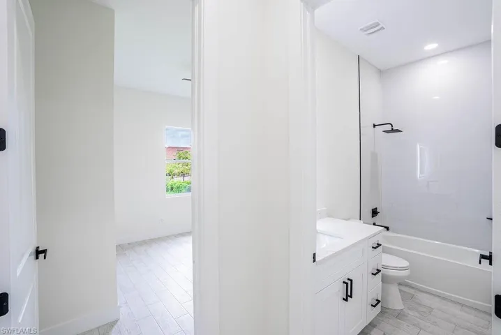 Full bathroom featuring hardwood / wood-style floors, washtub / shower combination, toilet, and vanity
