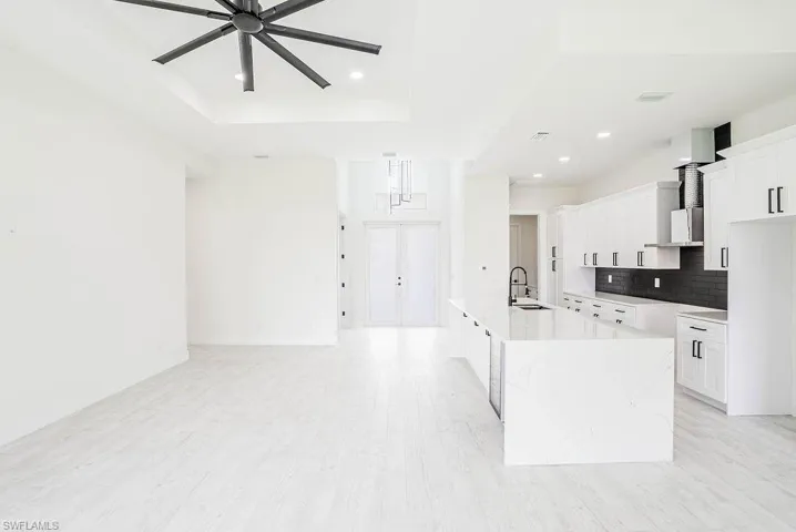 Kitchen featuring tasteful backsplash, sink, ceiling fan, a tray ceiling, and a spacious island