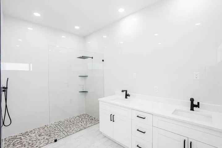 Bathroom featuring double sink vanity and a tile shower