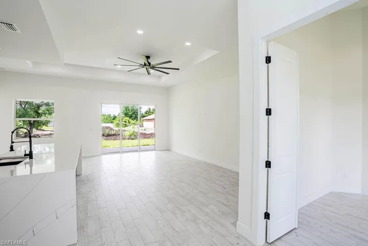 Spare room featuring a raised ceiling, light hardwood / wood-style flooring, and ceiling fan