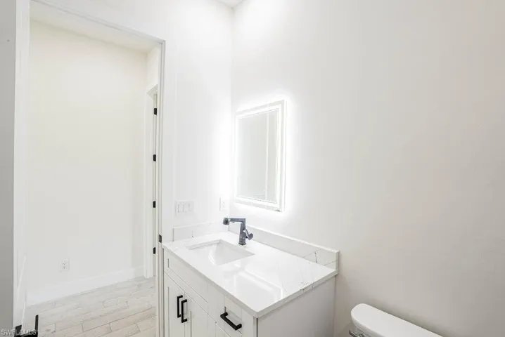 Bathroom with hardwood / wood-style floors, toilet, and vanity