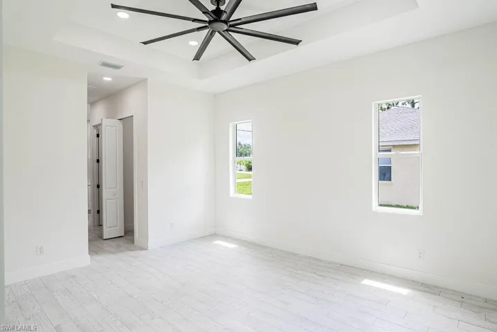Unfurnished room featuring ceiling fan, light hardwood / wood-style flooring, and a raised ceiling