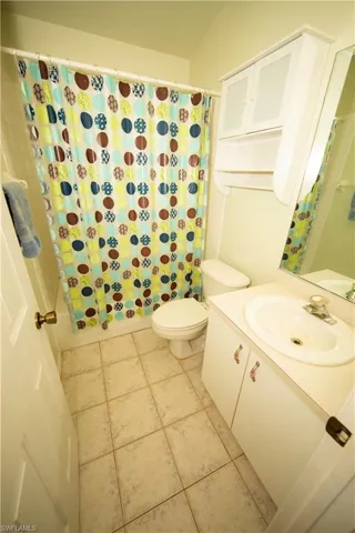 Full bathroom featuring tile patterned floors, shower / bath combo with shower curtain, vanity, and toilet