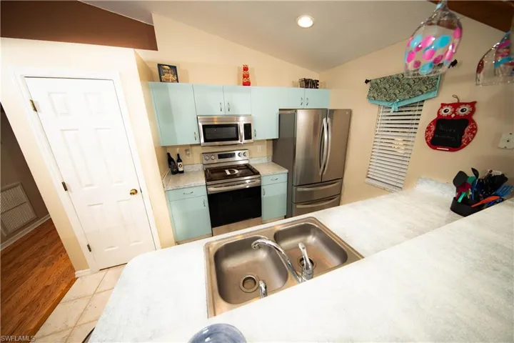 Kitchen with sink, tile flooring, lofted ceiling, and appliances with stainless steel finishes
