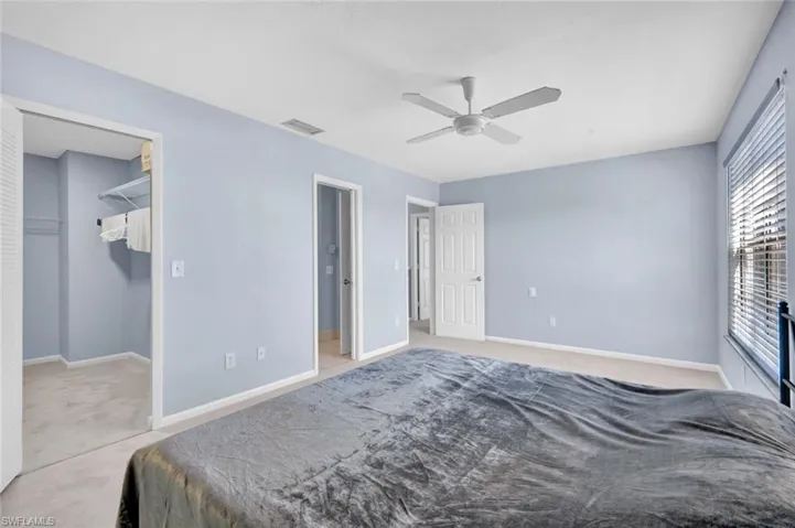 Bedroom featuring light carpet, a walk in closet, and ceiling fan