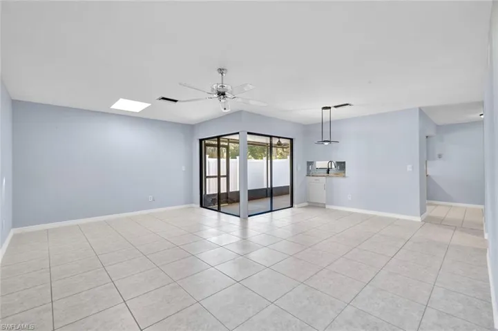 Unfurnished room with ceiling fan, light tile patterned floors, and a skylight