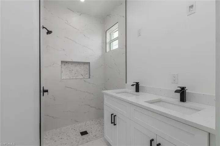 White vanity with dual integrated sinks, matte black faucets, and black hardware