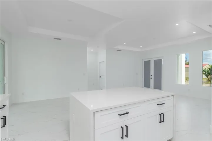 Kitchen island with a white countertop and white cabinetry featuring matte black hardware