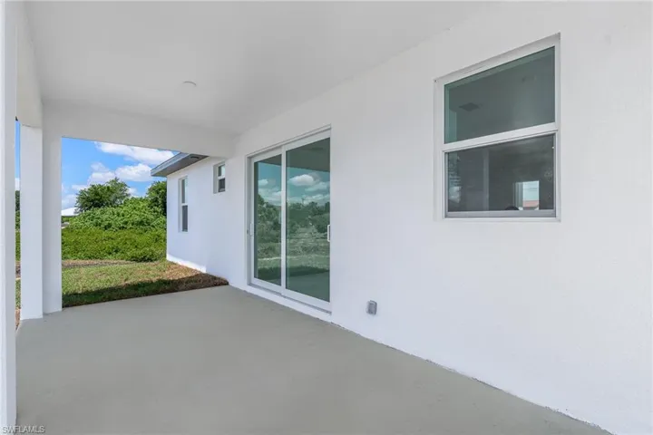 Covered patio with a concrete surface, featuring white stucco exterior walls