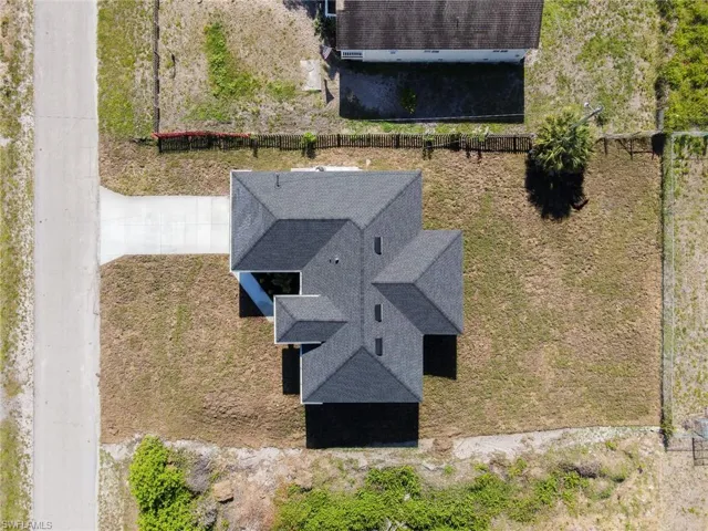 Newly constructed residence featuring a dark shingle roof and a concrete driveway
