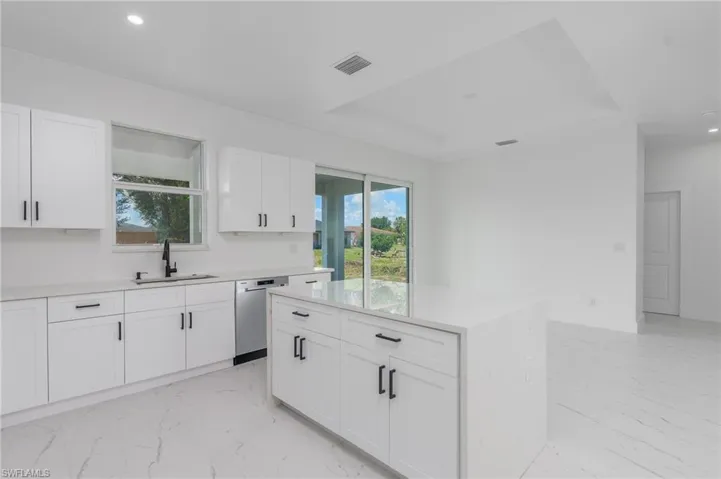 Modern kitchen featuring white shaker cabinetry, light countertops, and a central island