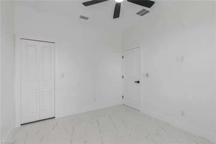Room featuring white walls, marble-finish flooring, and a ceiling fan with black blades