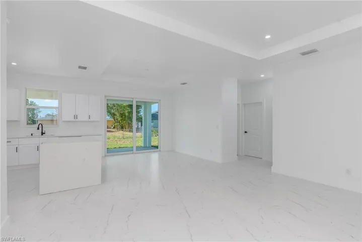 Open-concept living space featuring white tile flooring, recessed lighting, and a modern kitchen with white cabinetry and a central island
