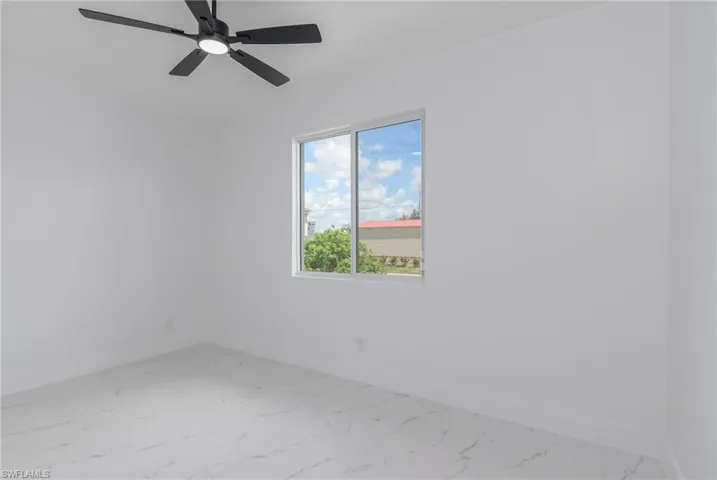 Spacious room featuring a contemporary ceiling fan with integrated lighting, a large window, white walls, and light-toned flooring