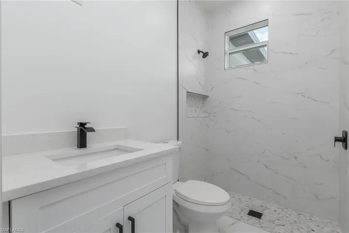 Bathroom featuring a white vanity with an integrated rectangular sink, matte black faucet, and white countertop