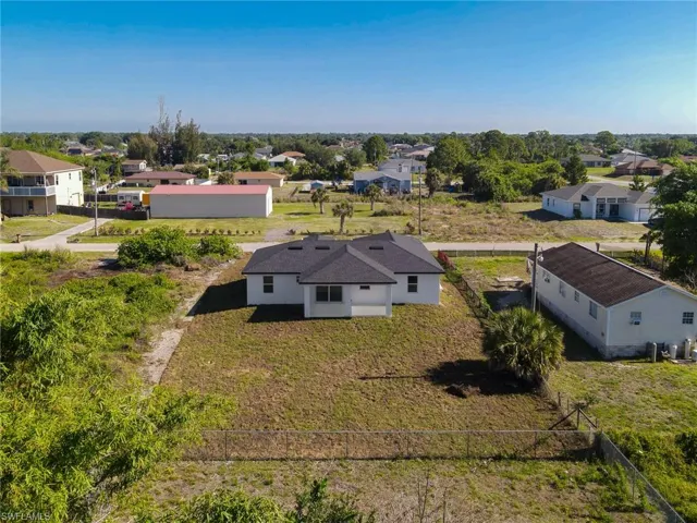 Newly constructed single-story residence with a black shingle roof, white exterior, and a spacious green yard