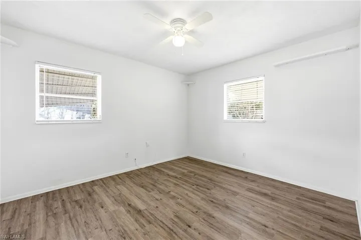 Unfurnished room with dark wood-style flooring and a ceiling fan