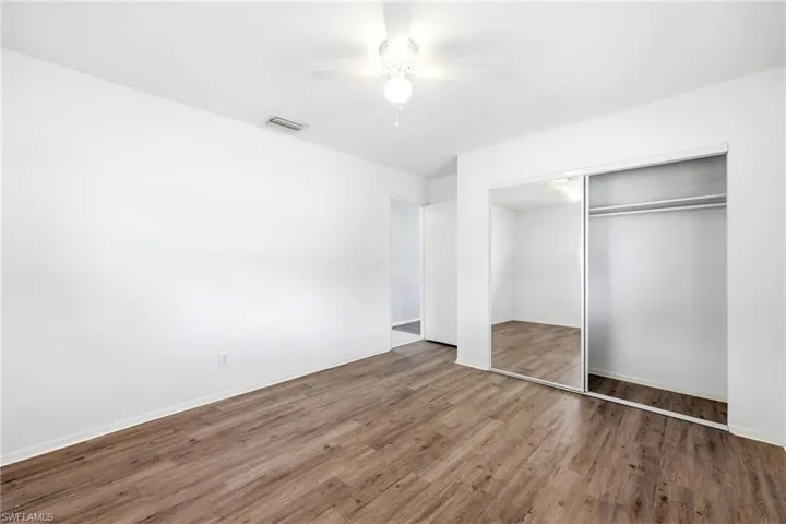 Unfurnished bedroom with dark wood-style flooring, a ceiling fan, and a closet