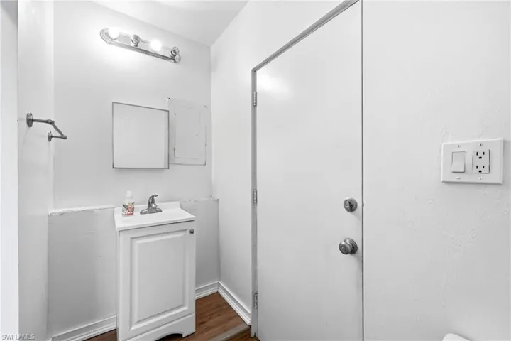 Half bathroom with vanity, dark wood-style floors, and electric panel