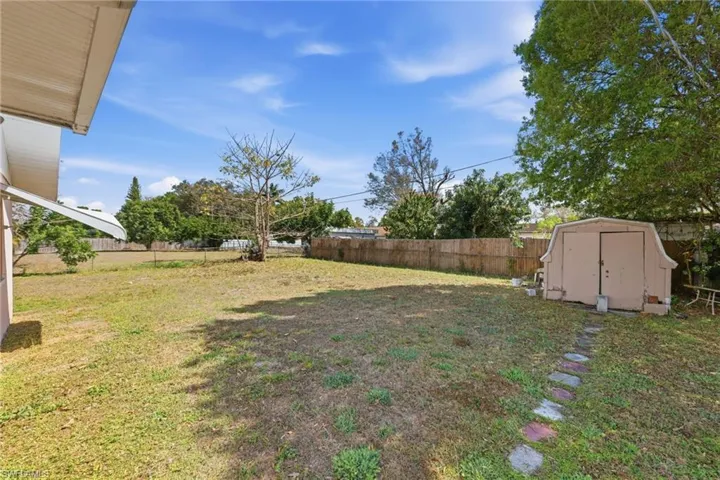Fenced backyard featuring a shed