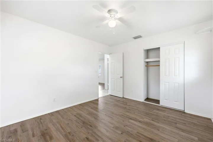Unfurnished bedroom featuring a closet, dark wood-type flooring, and ceiling fan