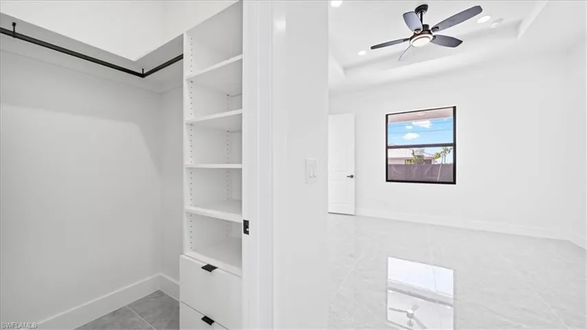 Walk in closet with a ceiling fan and a raised ceiling