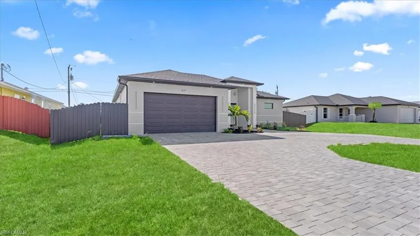 View of front of house featuring stucco siding, decorative driveway, an attached garage, and a gate