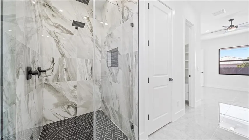 Full bath featuring a marble finish shower and a ceiling fan
