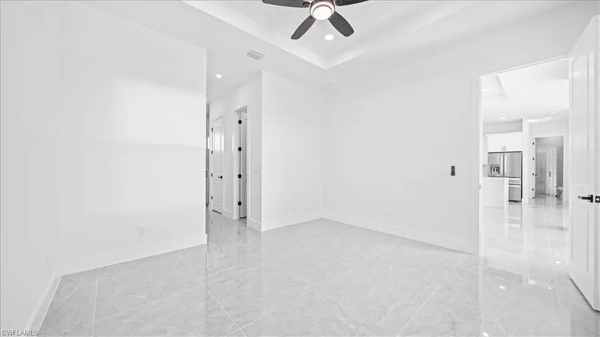 Empty room with a ceiling fan, recessed lighting, and a raised ceiling
